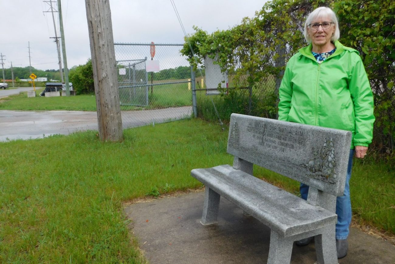 Woman stands in front of bench