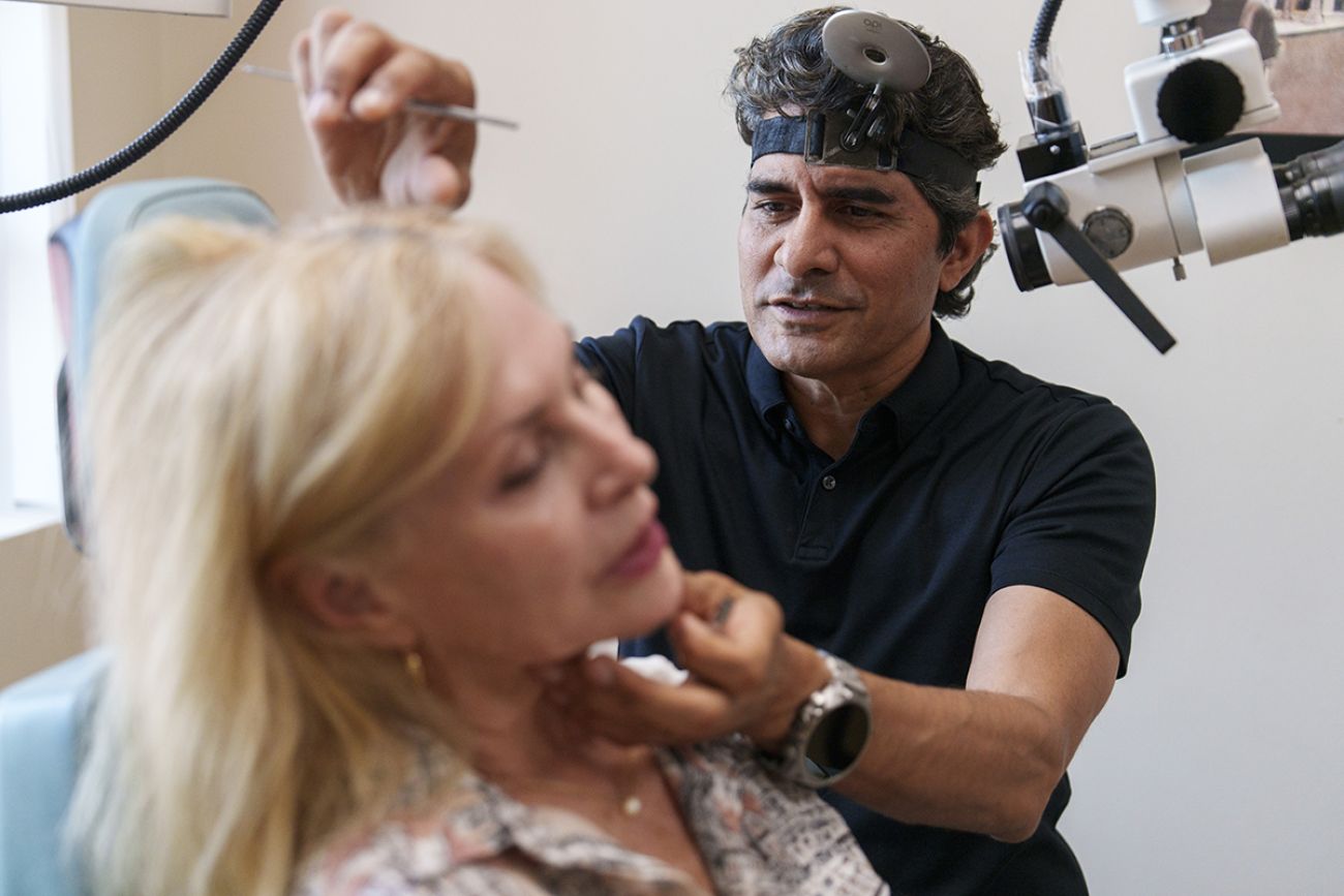 Dr. Bobby Mukkamala sees a woman patient in a medical office.