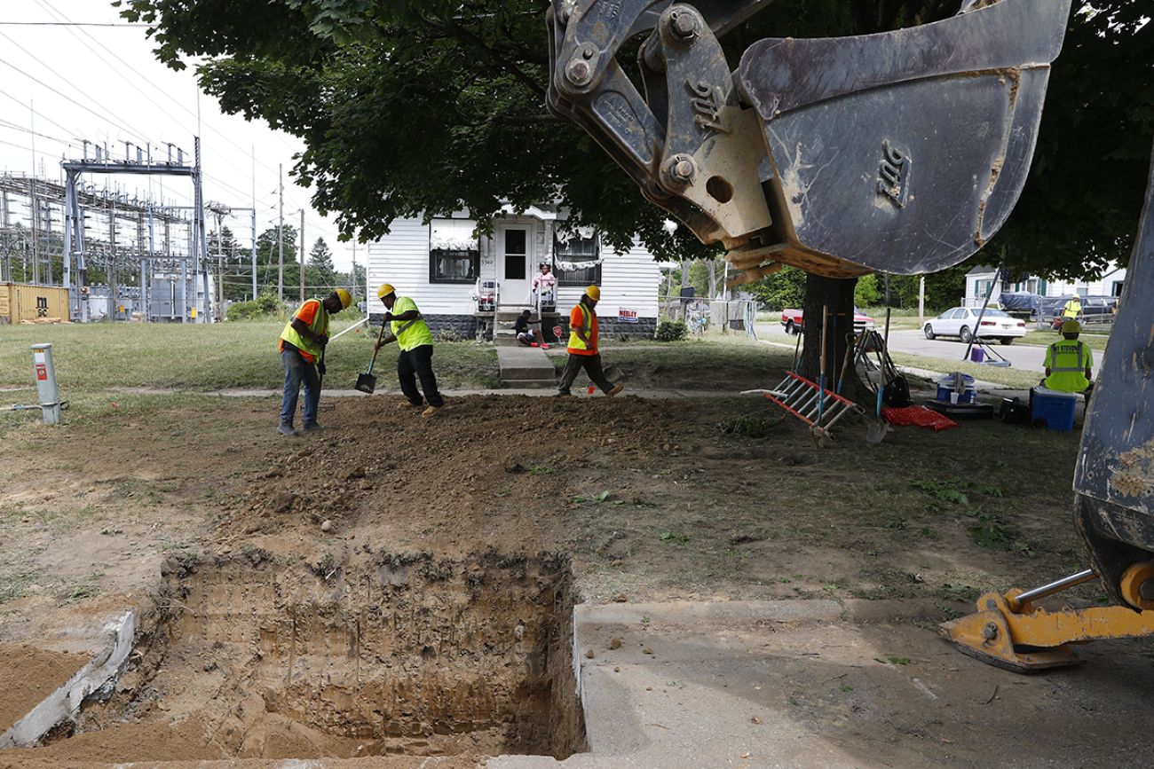 Workers work to fill a hole in front of a home in Flint, Michigan.