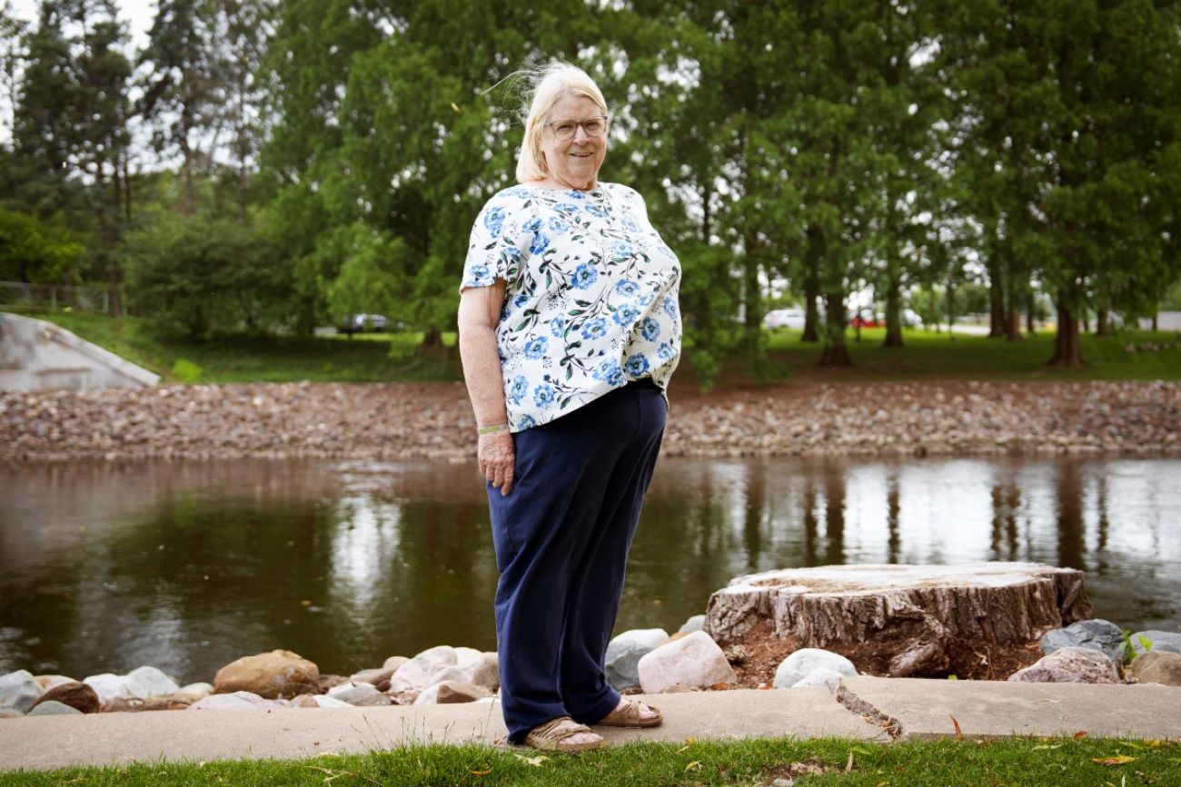 A woman poses for a photo alongside a river