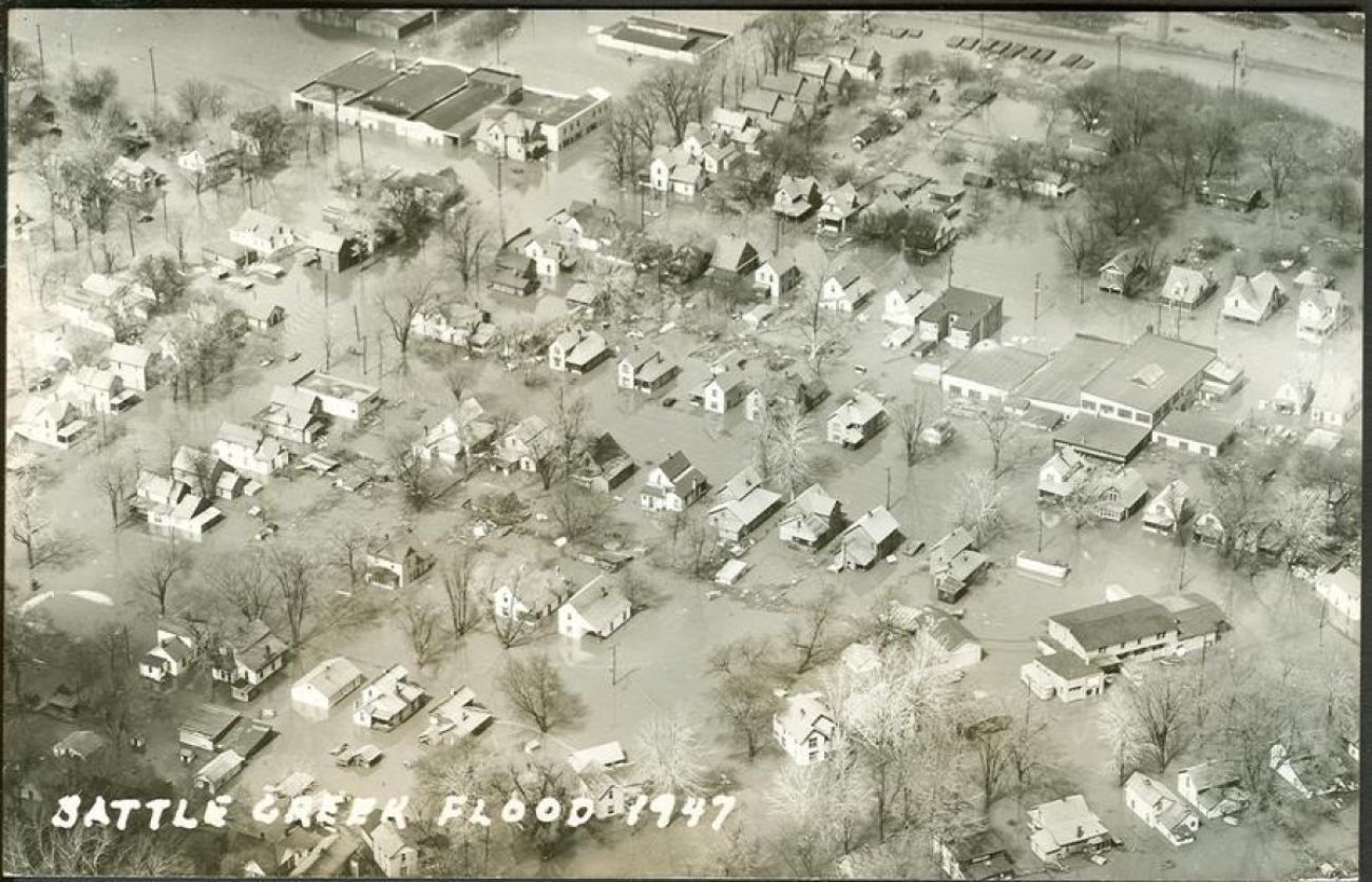 A black and white image of flooding surrounding many houses
