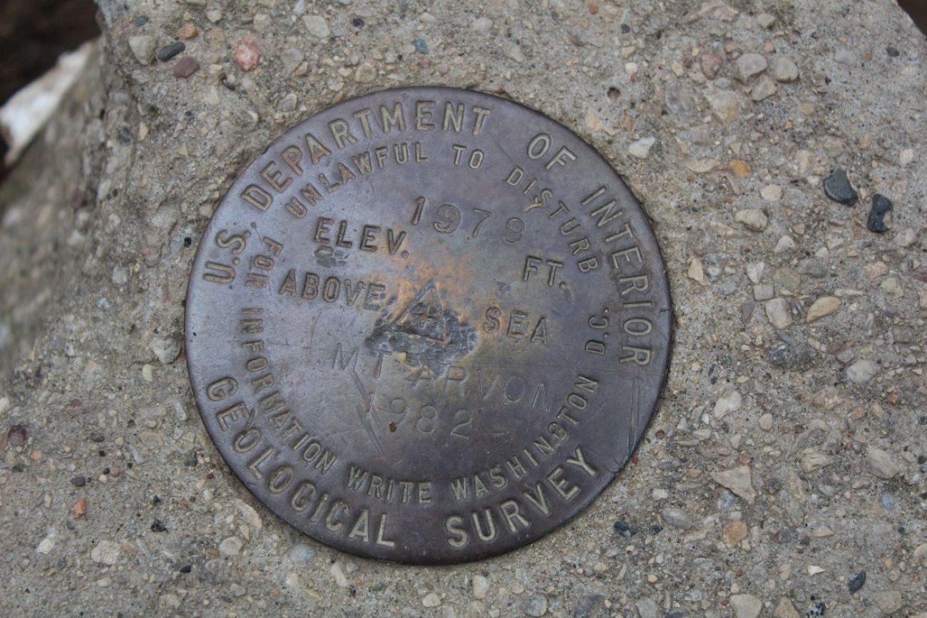 A metal marker set in stone informs visitors they've reached an elevation of 1,979 feet