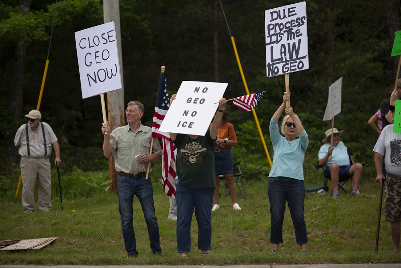 Demonstrators hold signs that say to close the ICE detention center.