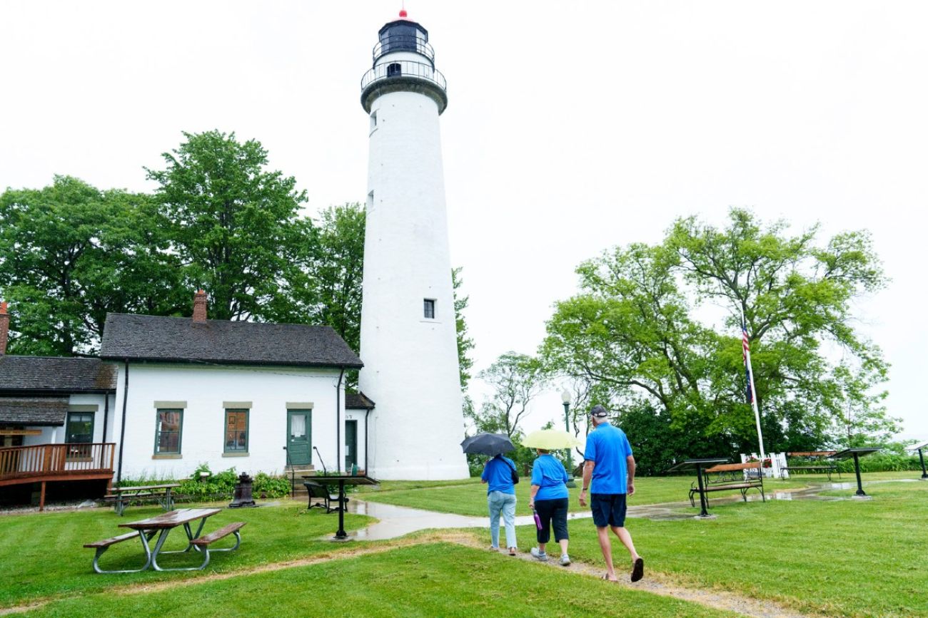 Two people walk toward a lighthouse