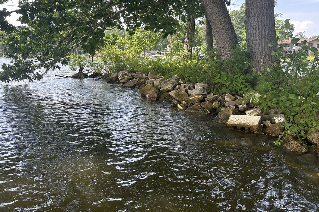 Broken concrete and cinder blocks line the shoreline of Brooks Lake in Michigan.