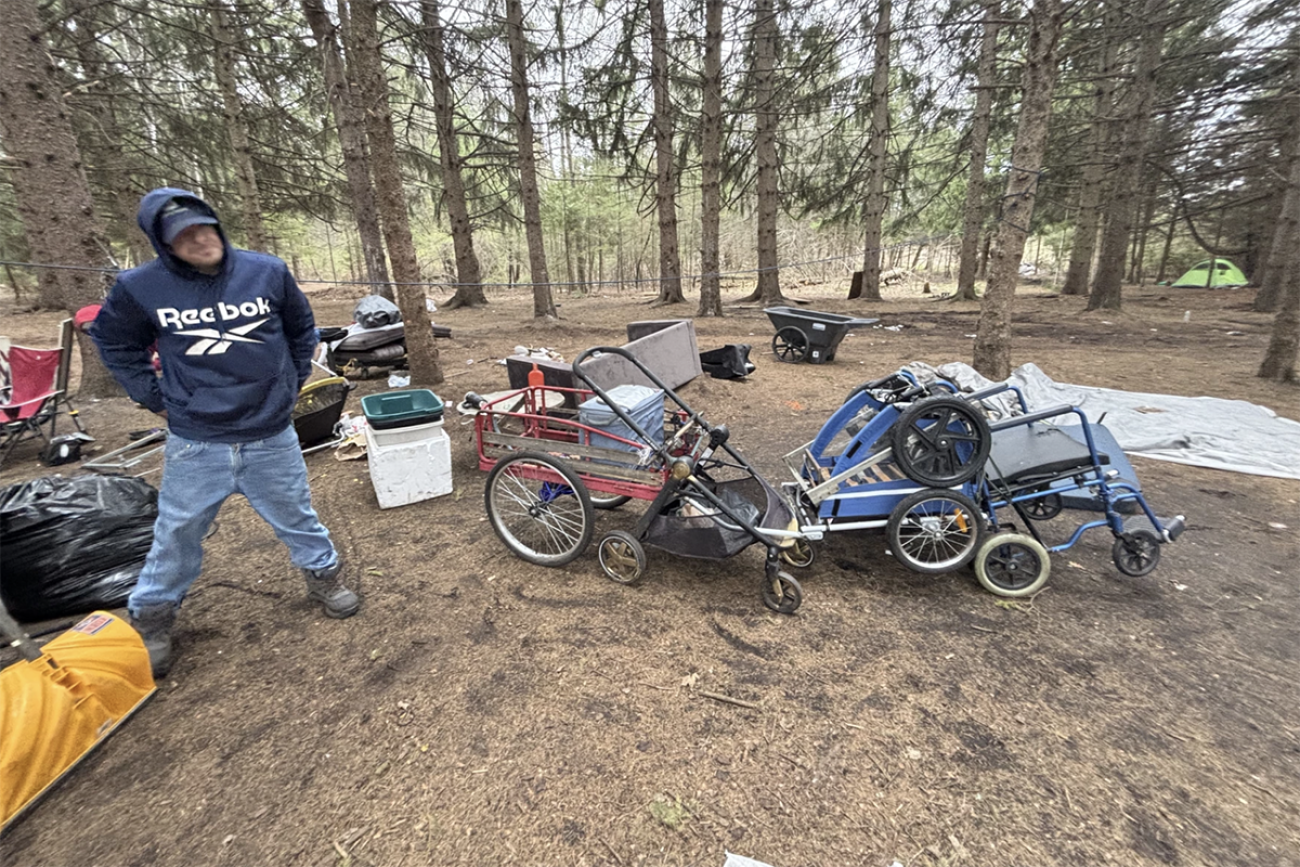 A man next to his personal items outside.