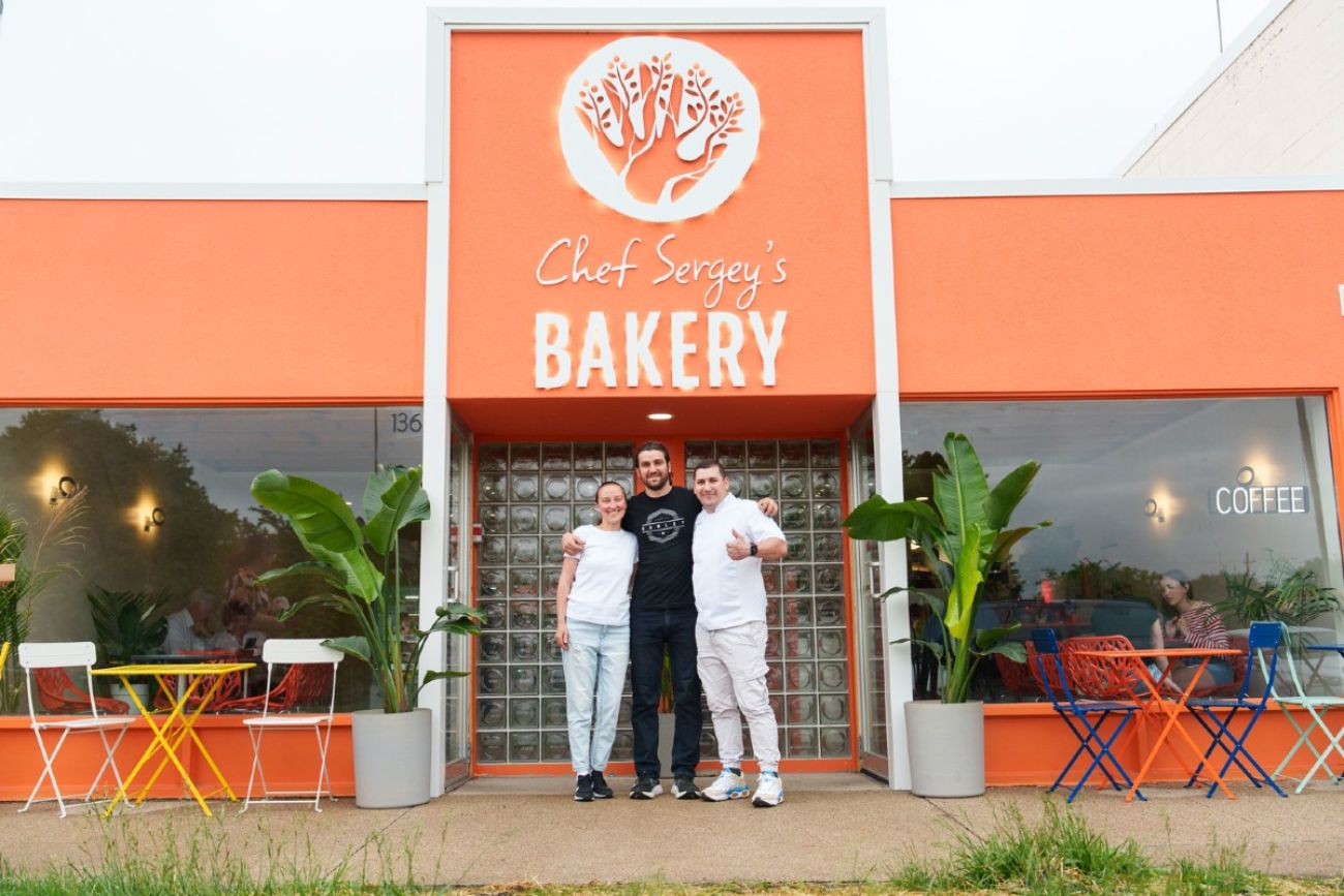 Three people stand in front of a Ukrainian Bakery