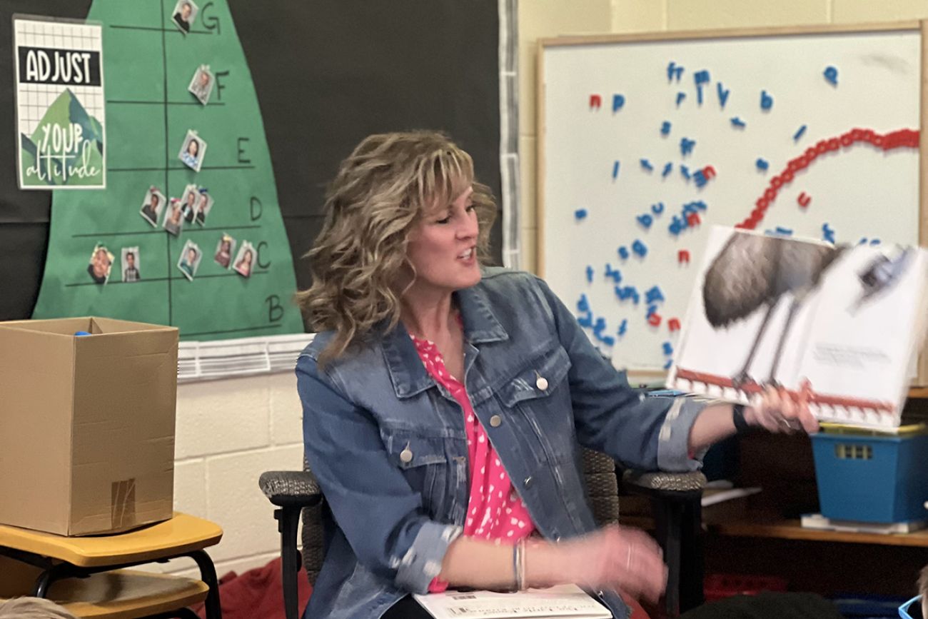 Christine Beachler holds up a book while reading it.
