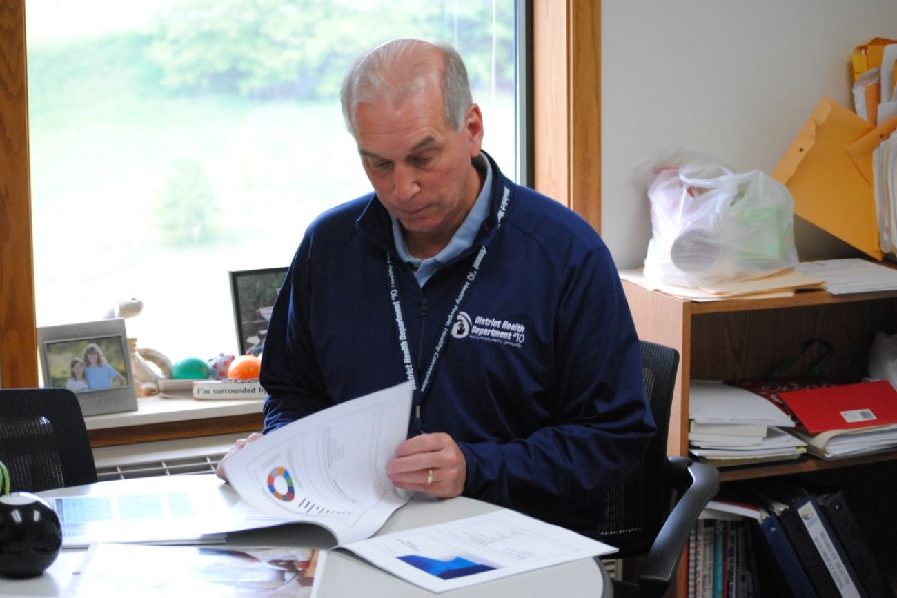 A man sits at a desk looking at paperwork
