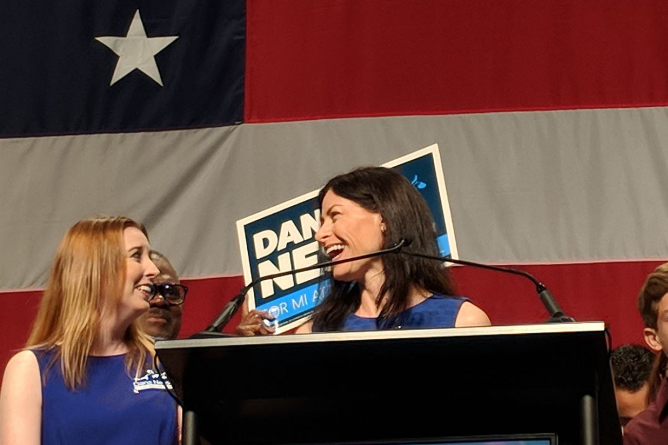 Attorney General Dana Nessel is on a stage next to her wife, Alanna Maguire.