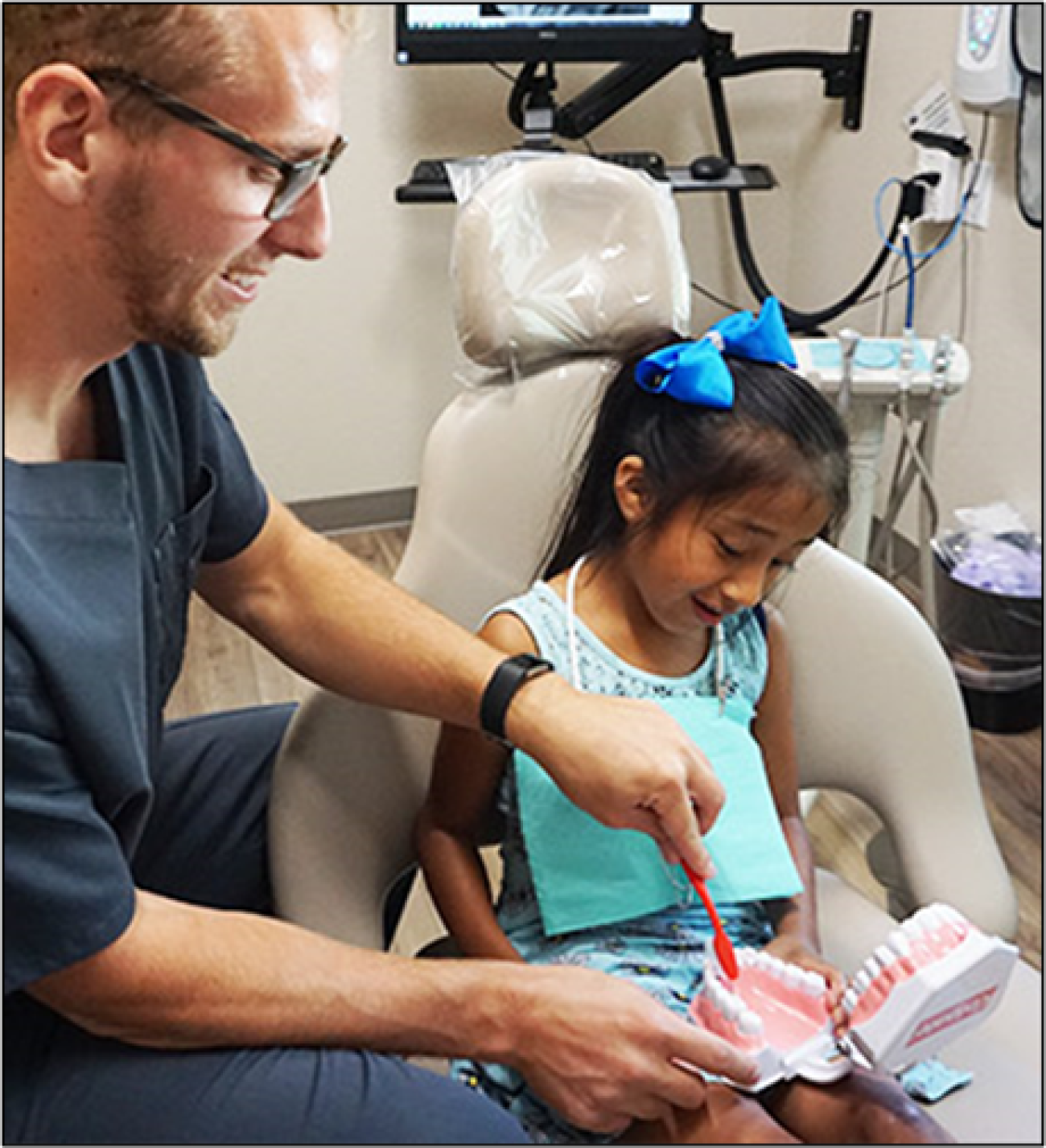 A man shows a young girl how to brush teeth.