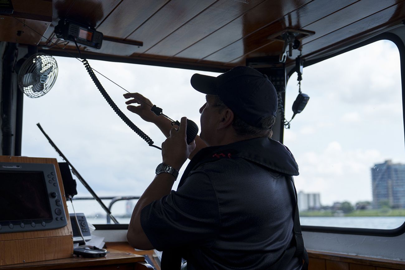 Sam Buchanan speaks into a communication device while on the M.S. Westcott.