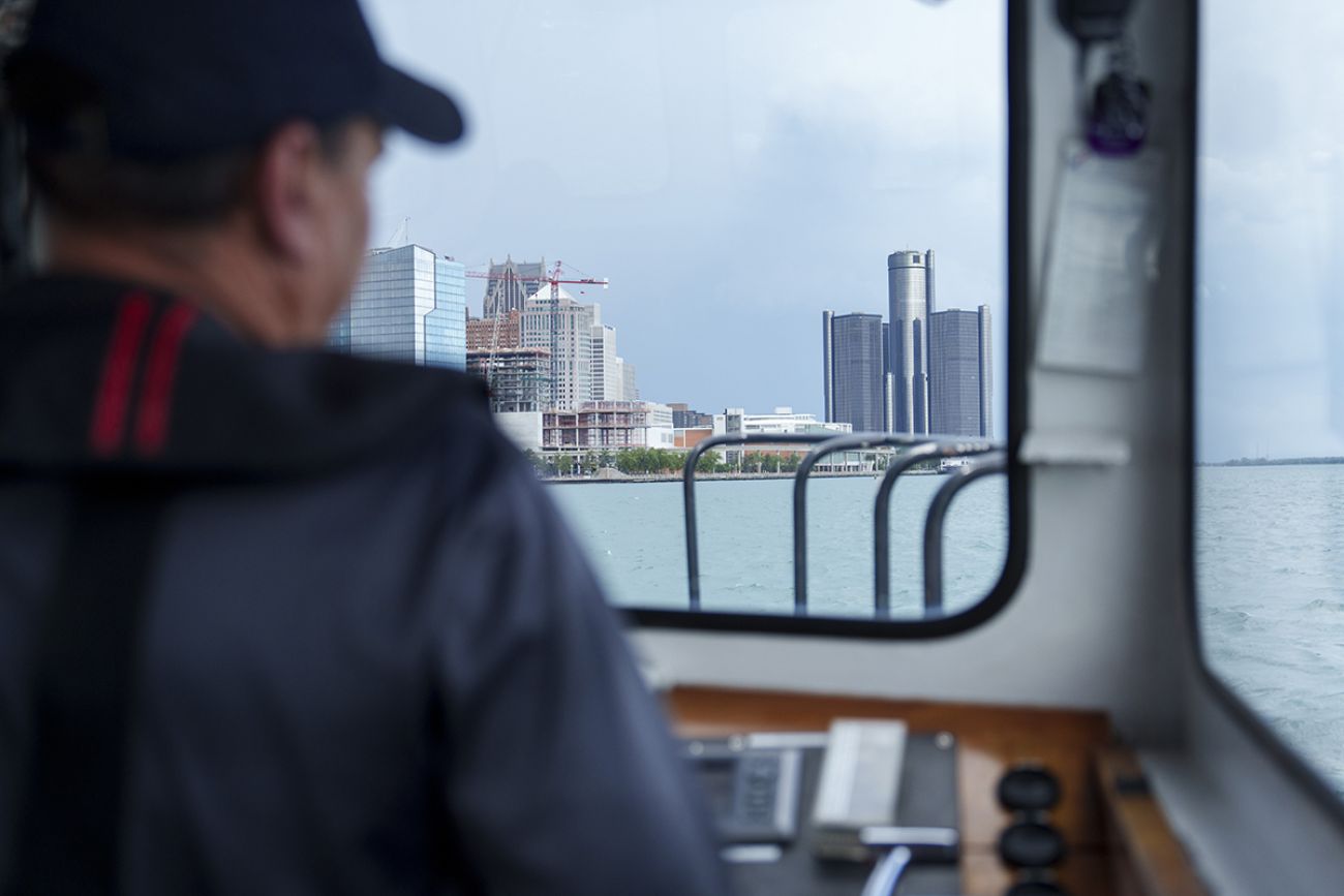 You can see the back of a man's head. In the window, you can see the Renaissance Center in Detroit.