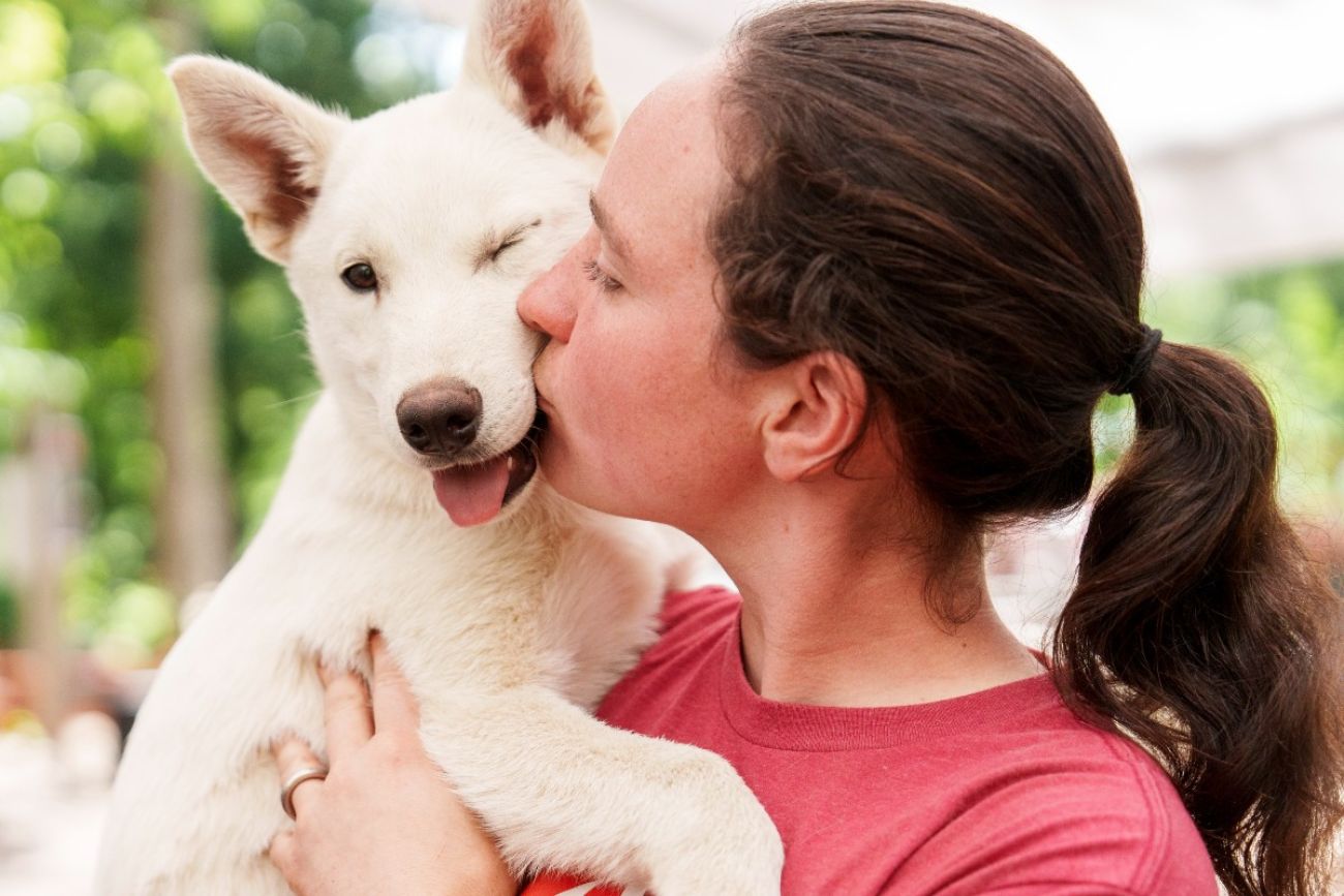 A woman holds a dog and kisses it