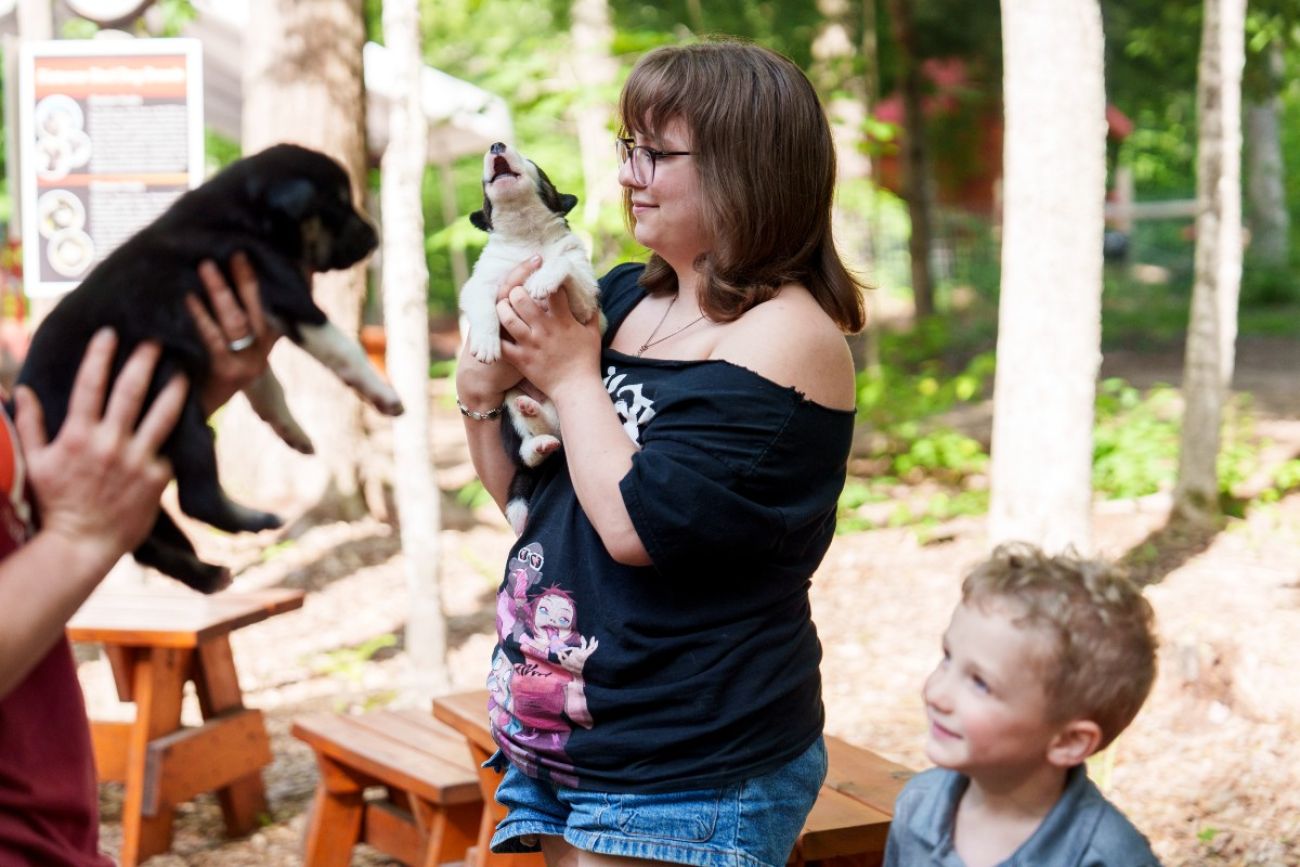 People smile as they hold puppies