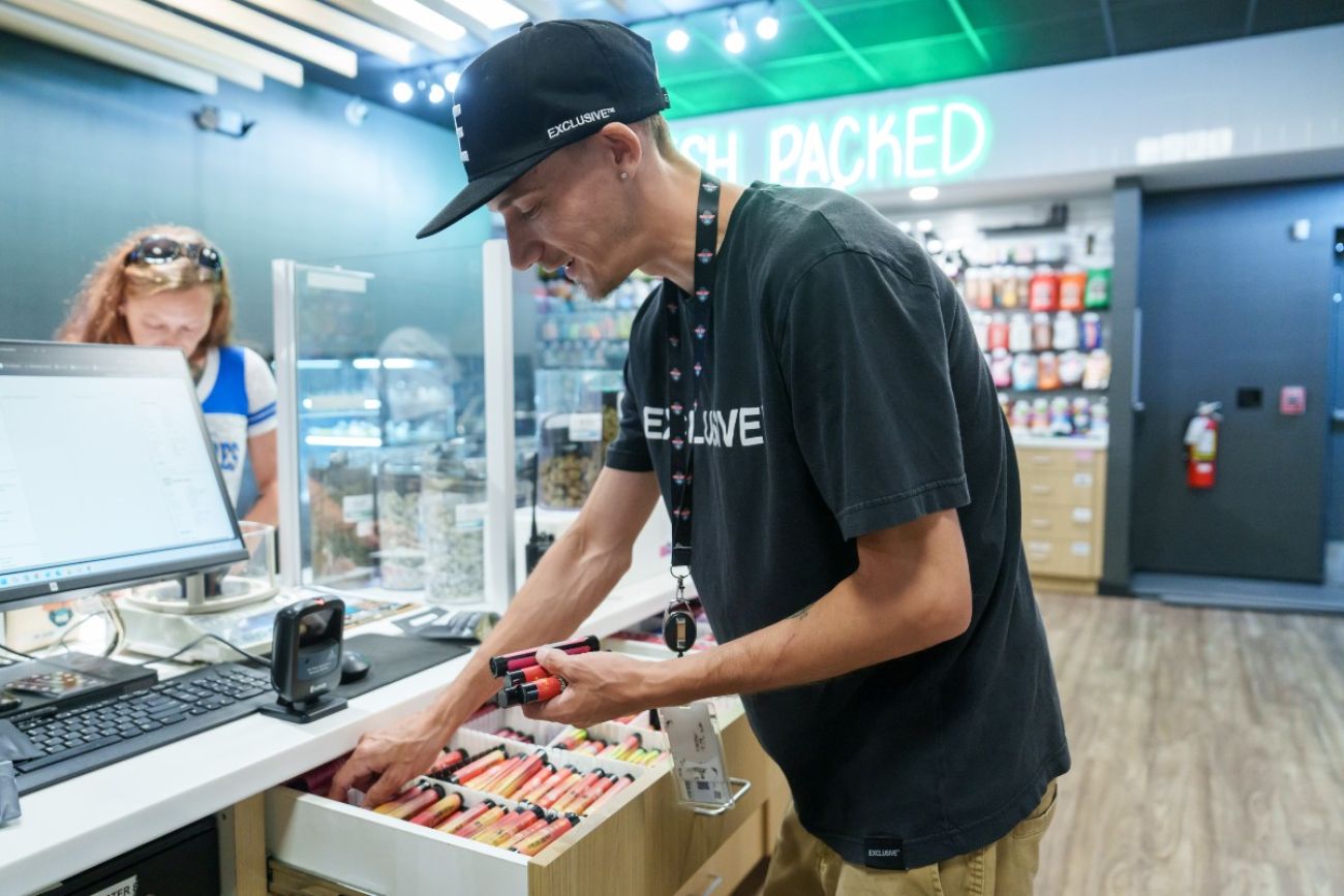 A man pulls marijuana products from a drawer inside a marijuana dispensary