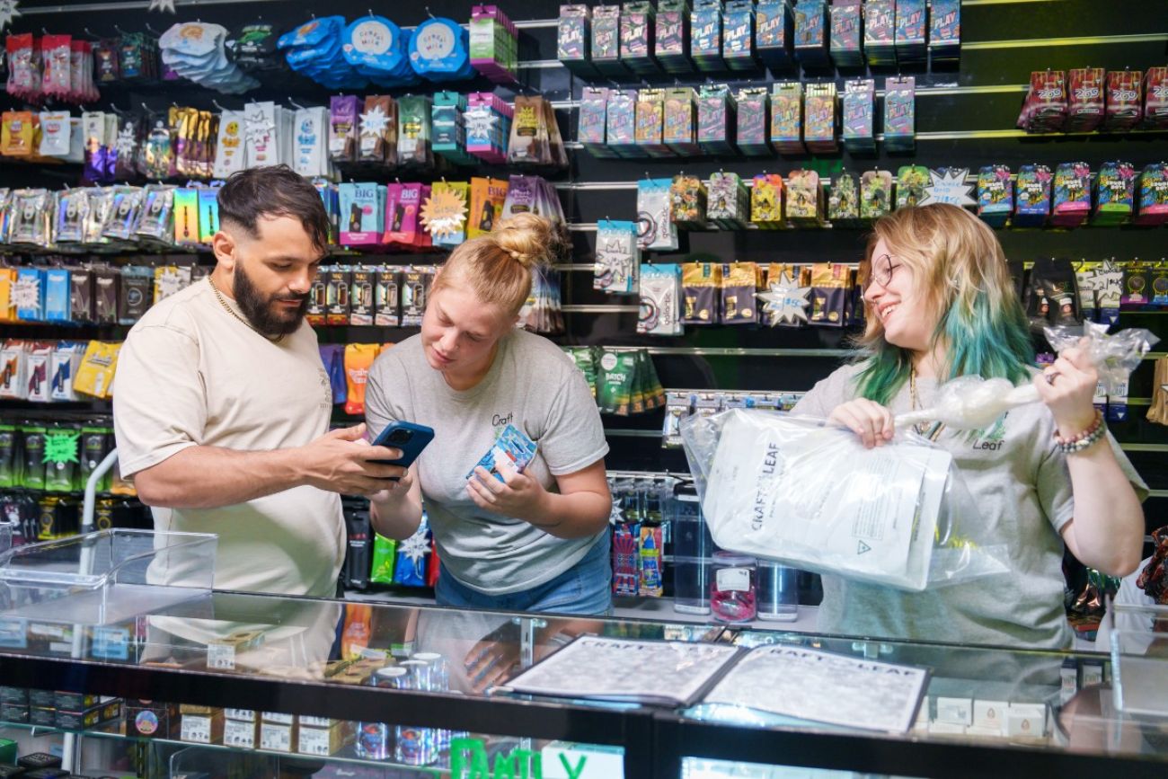 Three people talk behind a counter at a marijuana dispensary