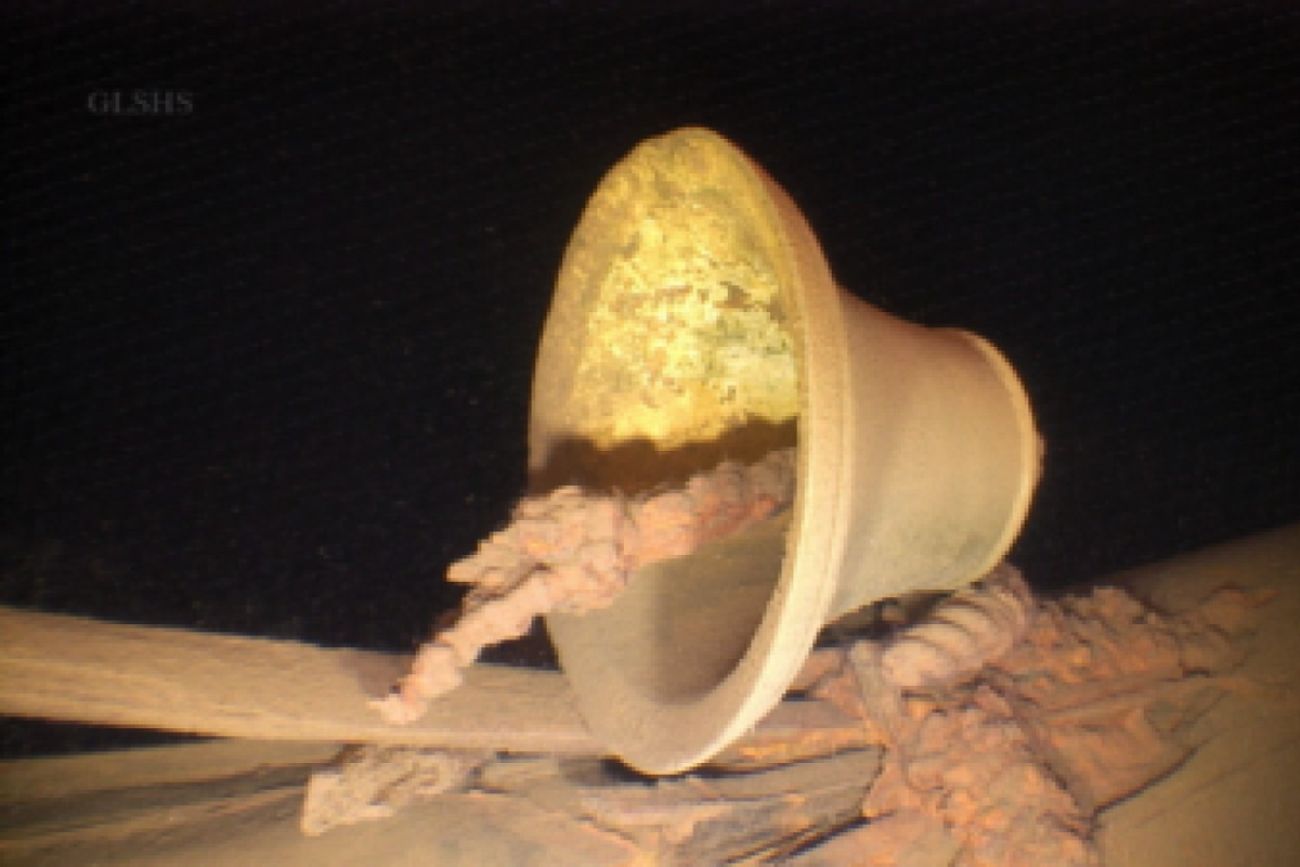 A bell is seen on a ship's deck underwater