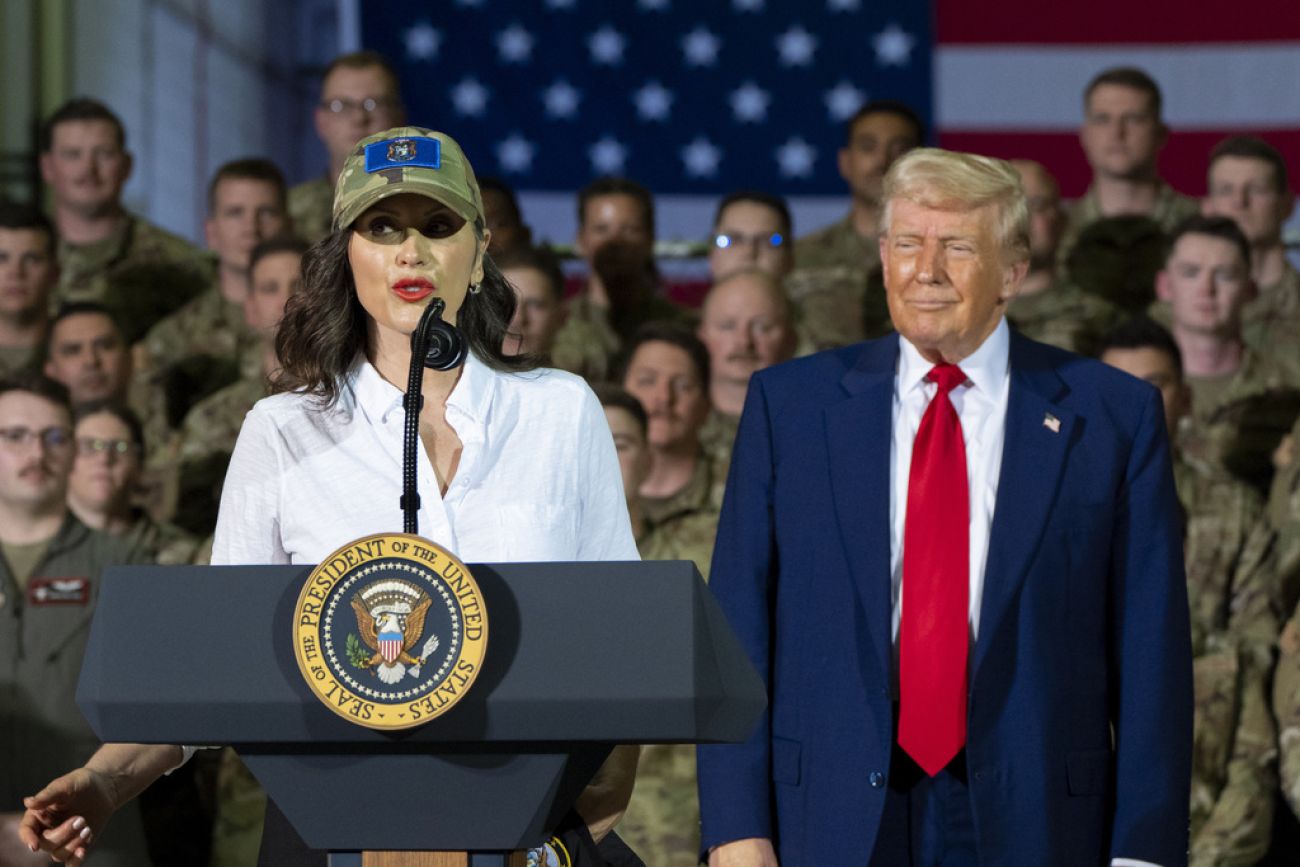 Michigan Gov. Gretchen Whitmer speaks at a podium. Donald Trump stands next to her.