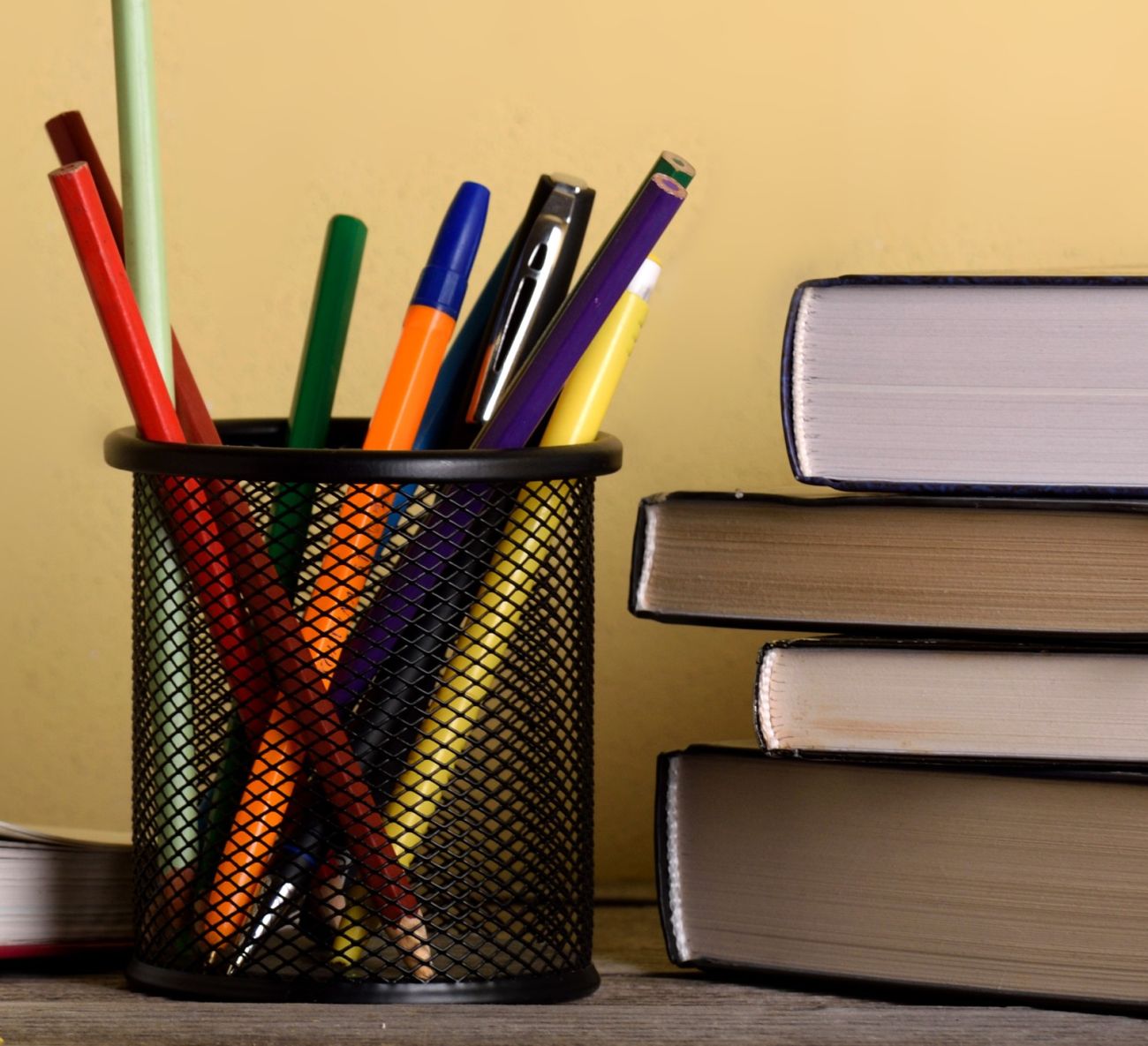Stock image of a cup of pens and a stack of books