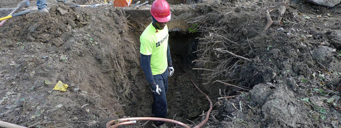 Kapus Brown runs copper line through a hole in the excavated dirt