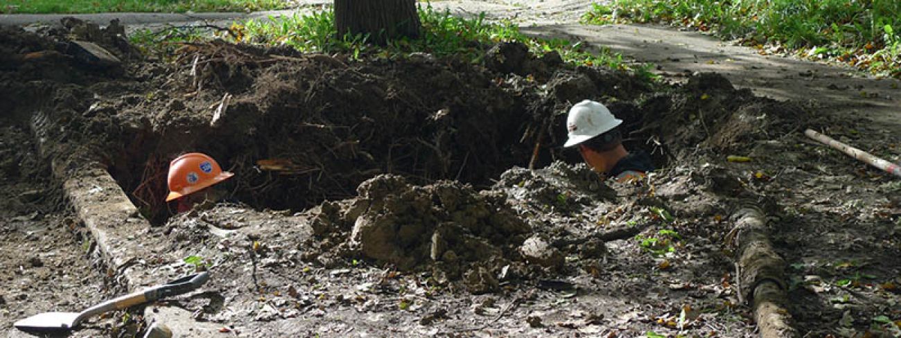 Two men working in an excavated hole
