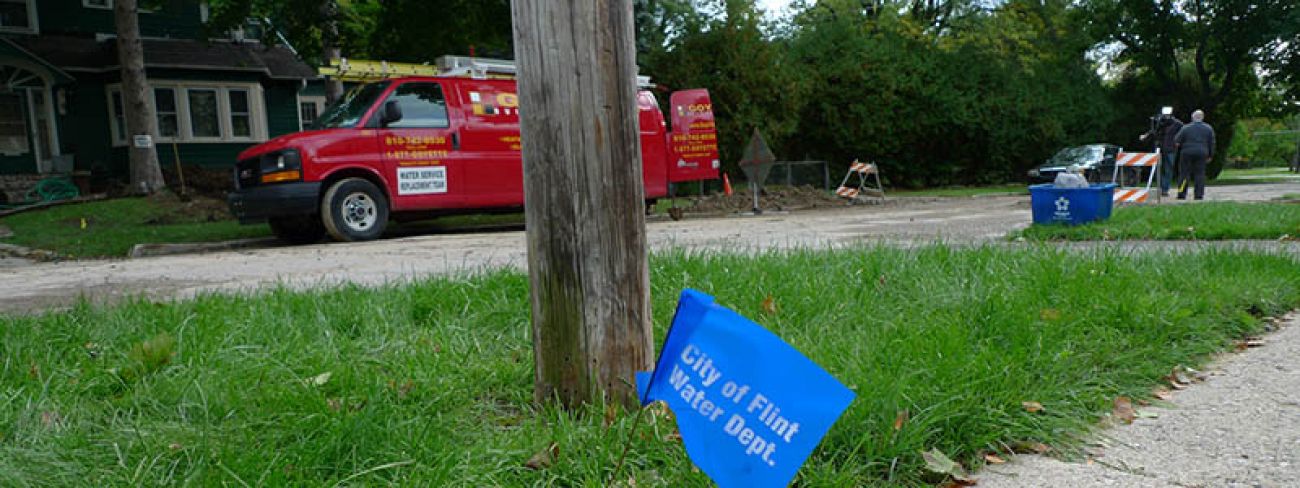 A City of Flint Water Dept. flag in the ground near a utility pole