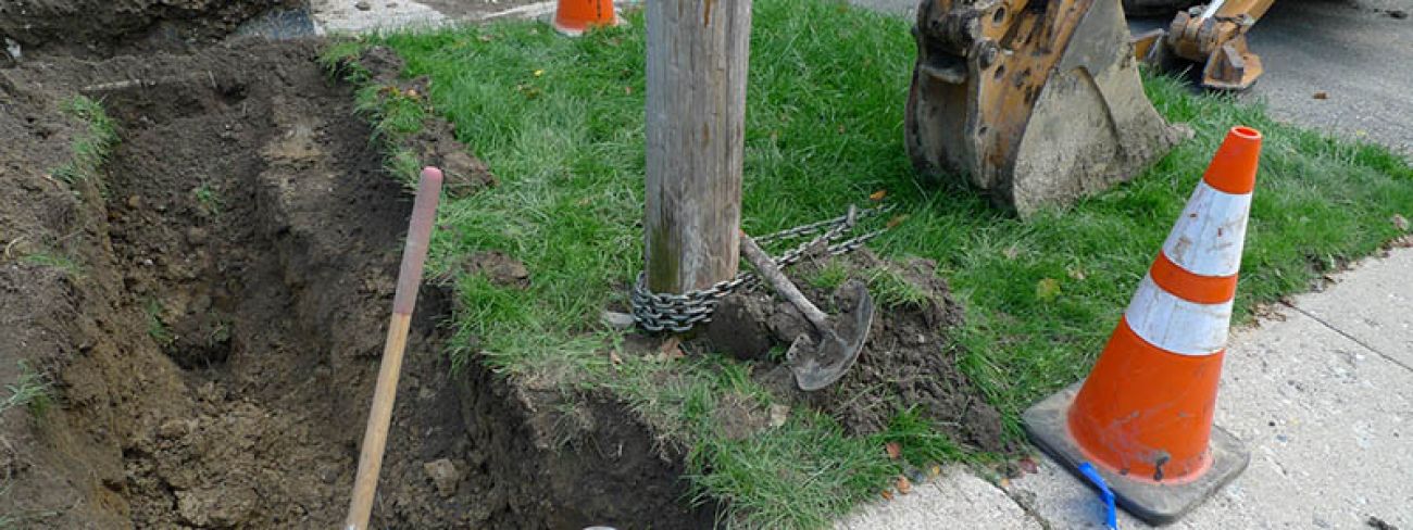 A chain wrapped around a utility pole near where crews have dug into the dirt