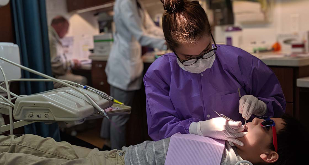 dental hygienist looks into child's mouth