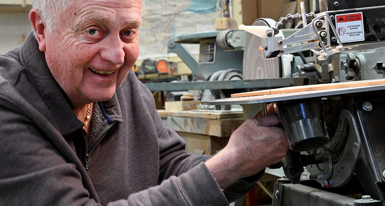 Neal Smith is smiling next to a saw
