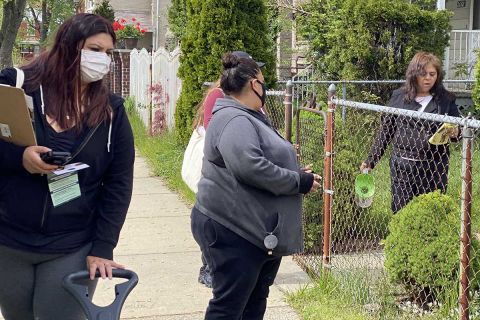 Almadelia Gonzalez, left, and Elizabeth Gonzalez inform a neighborhood resident about COVID-19 vaccination sites in Southwest Detroit.