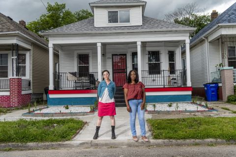 two woman in front of a house
