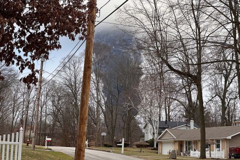 The rising smoke cloud after authorities released chemicals from a train derailment as seen from the ground in a nearby neighborhood.