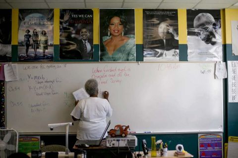 teacher in classroom writing on white board