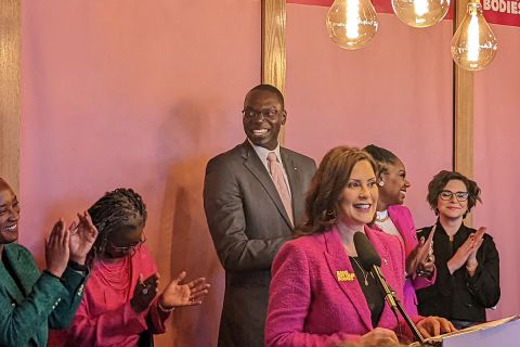Gov. Gretchen Whitmer at a press conference surrounded by people clapping