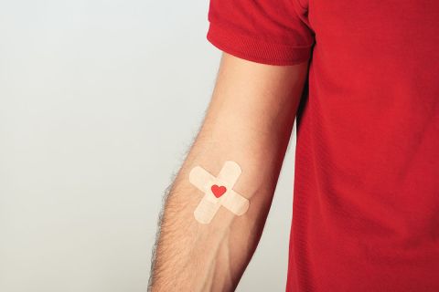 Partial view of patient in red t-shirt with plasters on grey background