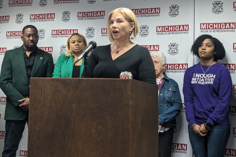 Nicole Beverly speaking at a podium, surrounded by other people