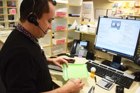 man by his desk with pills