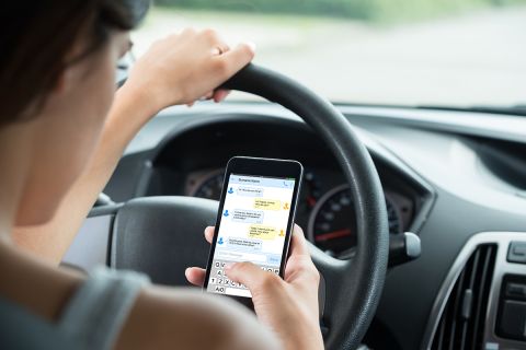 Close-up Of Woman Sitting Inside Car Typing Text Message On Mobile Phone