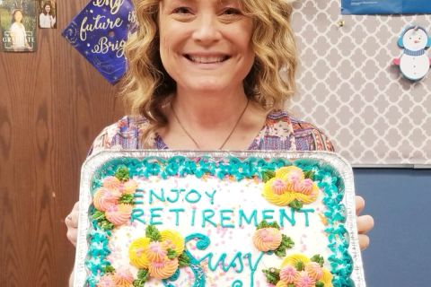 Susy Talentino holding up cake that says "happy retirement susy"