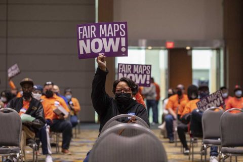 people holding signs that says "Fair Maps Now"