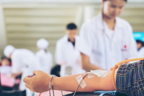 Nurse preparing to get blood from donors at blood donations center, selective focus on man's forearm