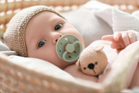 Cute newborn baby on white blanket in wicker crib, closeup