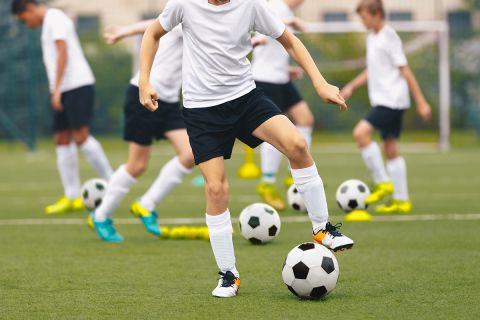 Group of teenage boys kicking soccer balls during a training session. 