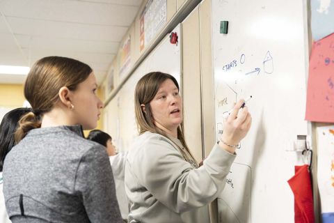 Boulan Park Middle School math teacher Jordan Baines writing on whiteboard
