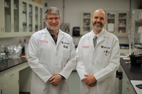 Two men stand side by side in a lab