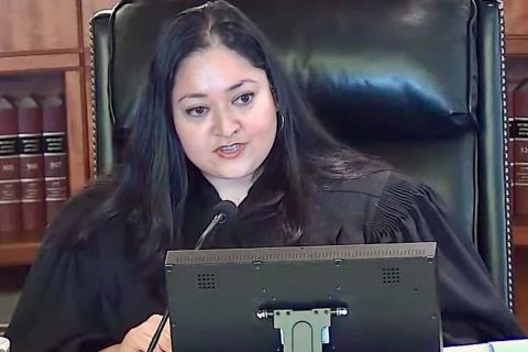 A judge sitting down, talking into a microphone
