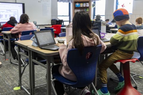 Children are working at their desks in a classroom. 