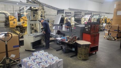 Mailroom crew members take copies of the Lenawee Voice off the press in the Tecumseh Herald newsroom