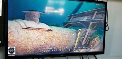 A photo of the Line 5 pipeline on a TV screen. You can see the pipeline is in open water.